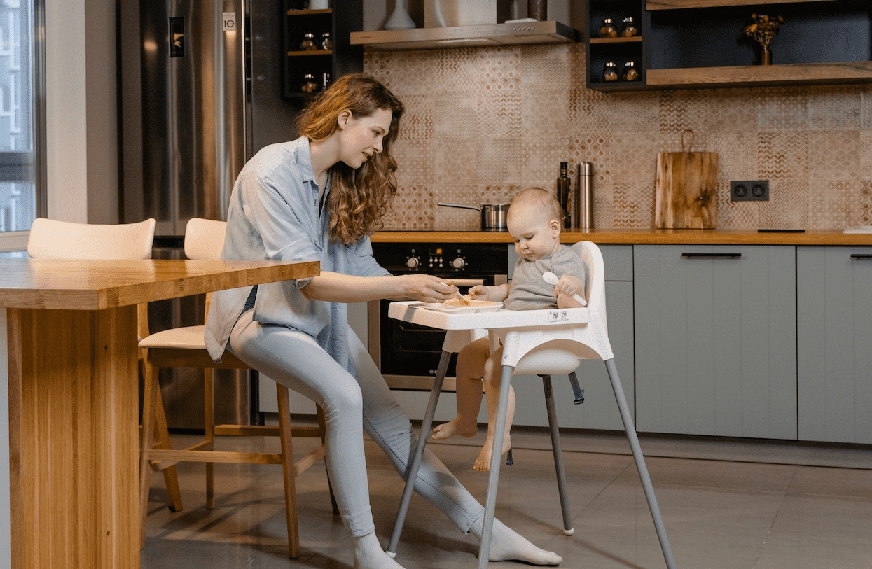 toddler sitting on a high chair while being fed