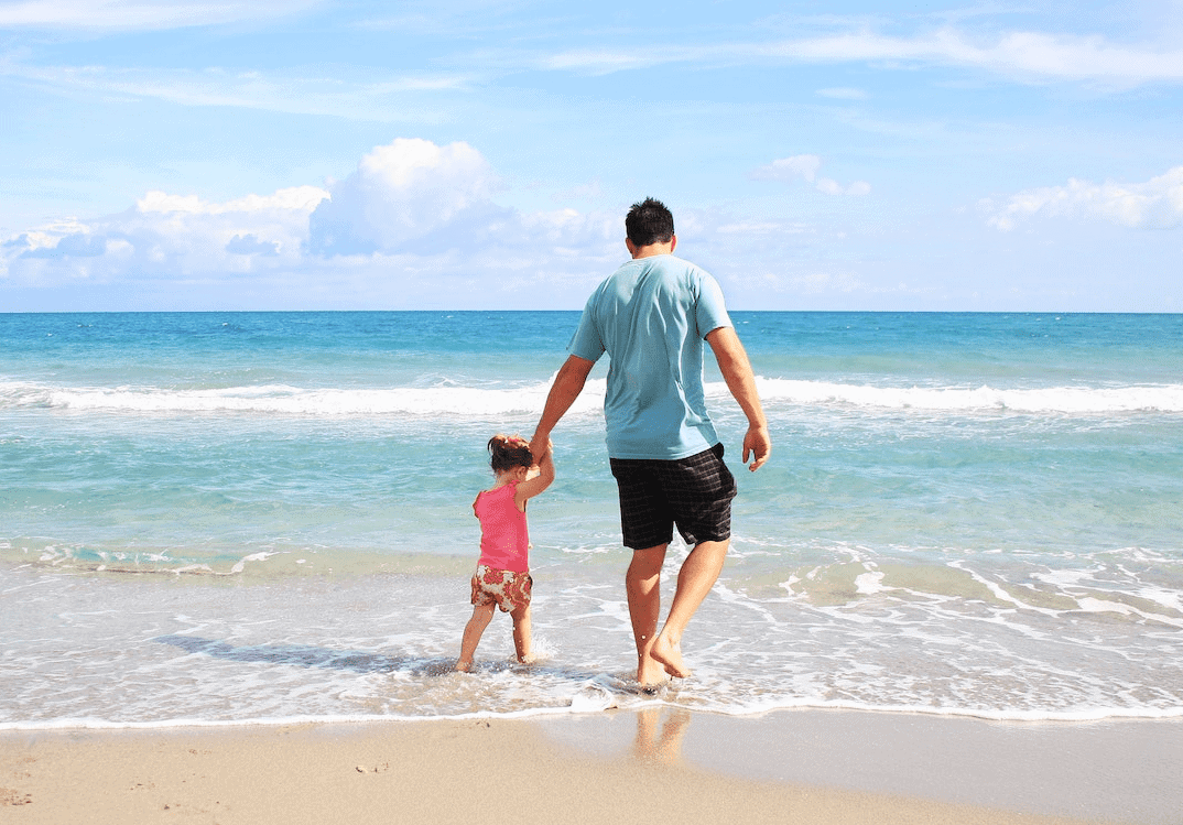 dad and daughter walking on beach