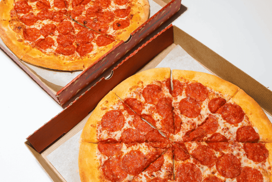 two pepperoni pizzas on a table