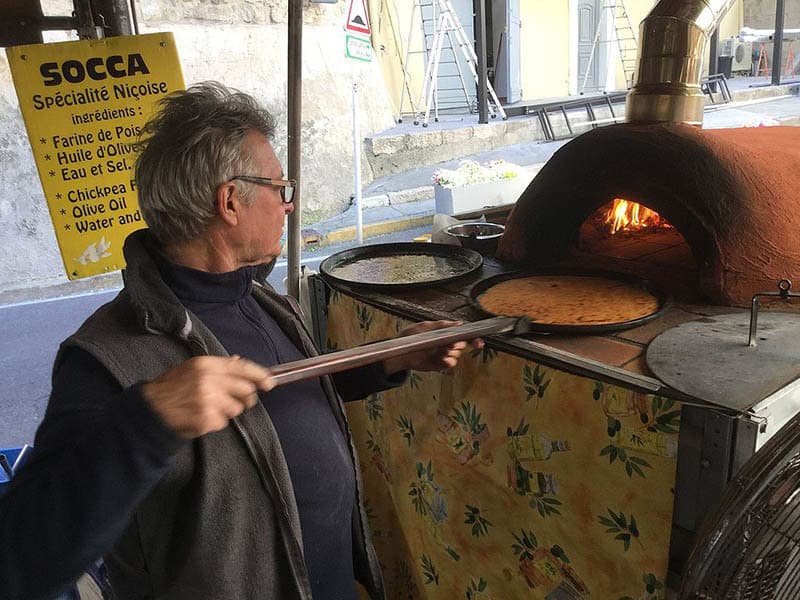 photo of vendor cooking Socca, a traditional niçoise dish from nice France