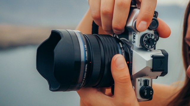 OM System OM-5 II camera held vertically in photographer's hands