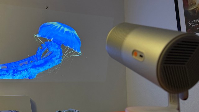 The XGIMI MoGo 4 portable projector showing an image of a jellyfish, on a black background, but the background has faded into the wall