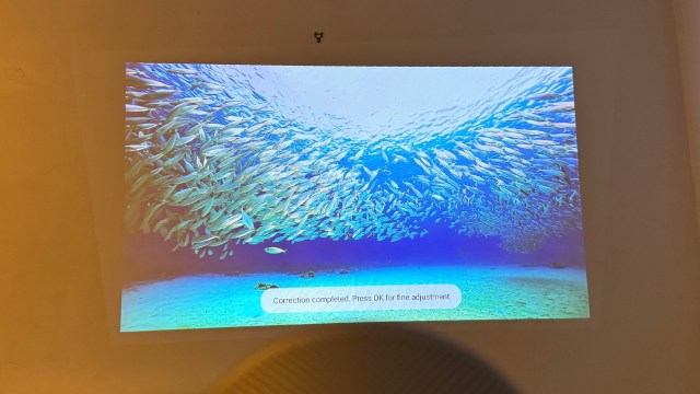The XGIMI MoGo 4 portable projector showing an image of a fish shoal, with test saying that image correction has completed