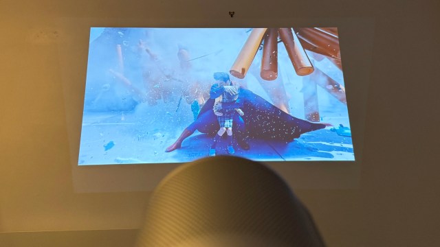 The XGIMI MoGo 4 portable projector showing an image of Superman saving a child, projected on a wall