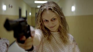 Heather Graham holding a gun and looking frantic in the movie Suitable Flesh