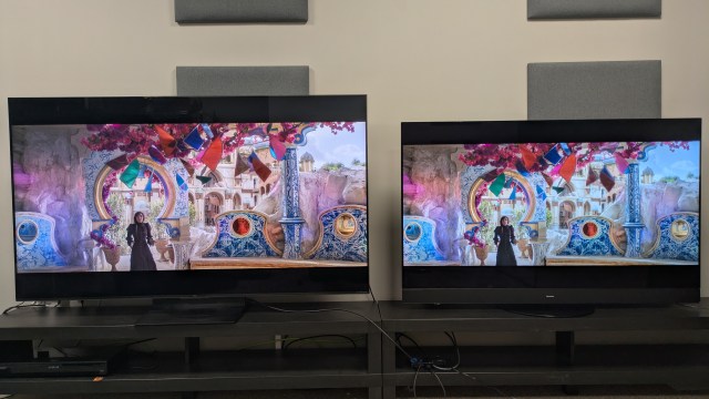 TCL C7K mini-LED left and Panasonic MZ1500 OLED right displaying a Elphaba in a brightly colored room from Wicked on screen