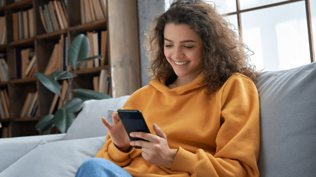 hispanic teen girl checking social media holding smartphone at home.