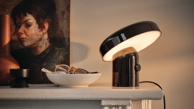 IKEA BLOMPRAKT speaker lamp on a white fireplace with a bowl beside it and a painting on the wall behind it