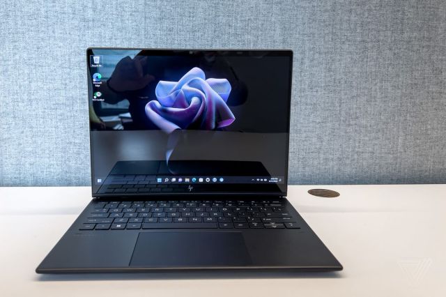 The HP Dragonfly Folio G3 on a desk in laptop mode, open. The screen displays a purple flower on a black background.