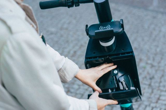 Rider placing helmet into scooter compartment