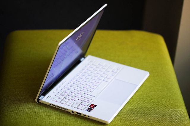 The Asus ROG Zephyrus G14 half open, angled to the right, on a green fabric bench.