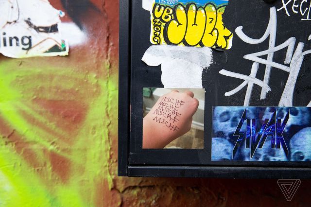 Stickers and spray paint adorn an exterior building wall