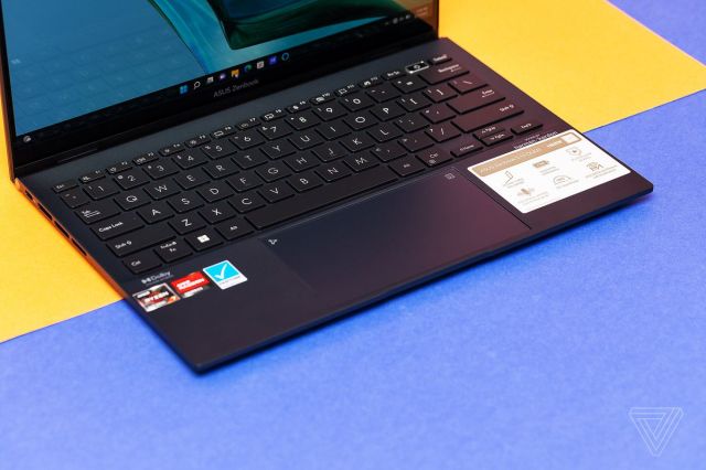 The Asus Zenbook 13 S OLED keyboard seen from above and to the left on a blue and yellow surface.