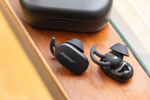 The Bose QuietComfort Earbuds on a table beside the carrying case.