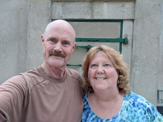 A photo of Tom and Mary smiling, taking a selfie photo outside their bunker.