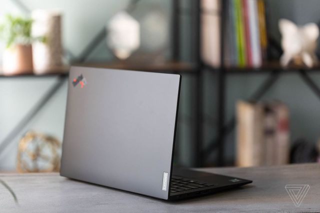 The Lenovo ThinkPad X1 Carbon Gen 9 on a table in front of a bookshelf, facing away from the camera, angled to the right.