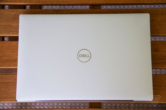 The Dell XPS 13 OLED lid on a wooden table seen from the top.