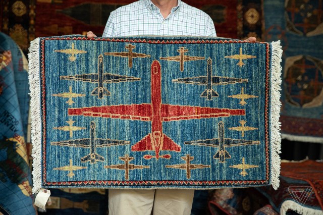 The blue rug has a large red drone in the center, surrounded by a series of smaller drones in other colors.