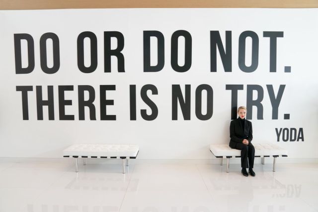 Elizabeth Holmes sitting before a Yoda quote mural as she’s about to be interviewed.