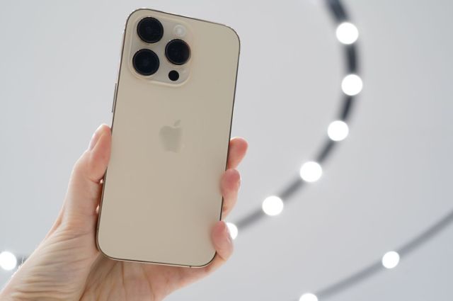 Image of someone holding an iPhone 14 Pro in the air.