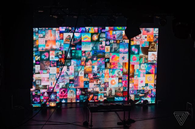 A cropped section of the Beeple is displayed on stage. Stage equipment sits in front of the display.