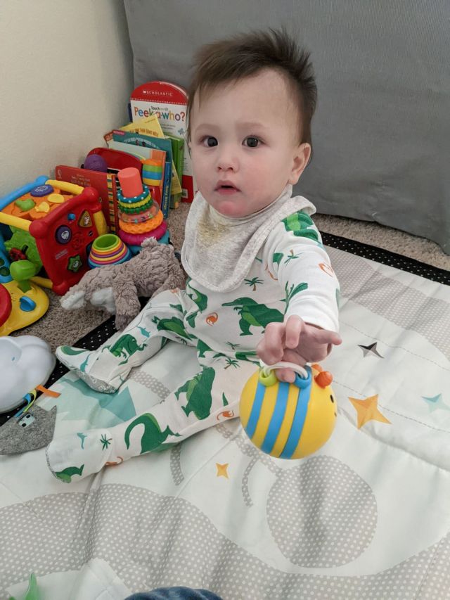 Baby holding a bee toy looking at camera