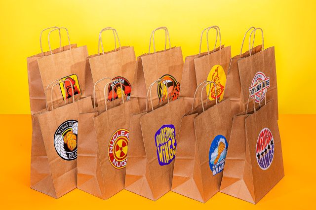 An image of ten bags in two rows of five, each with a different made up chicken wing restaurant logo, against a yellow backdrop.