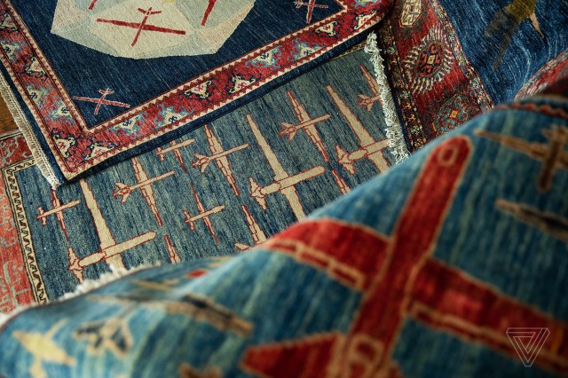 A series of overlapping blue and red rugs depicting drones of different sizes in different patterns.