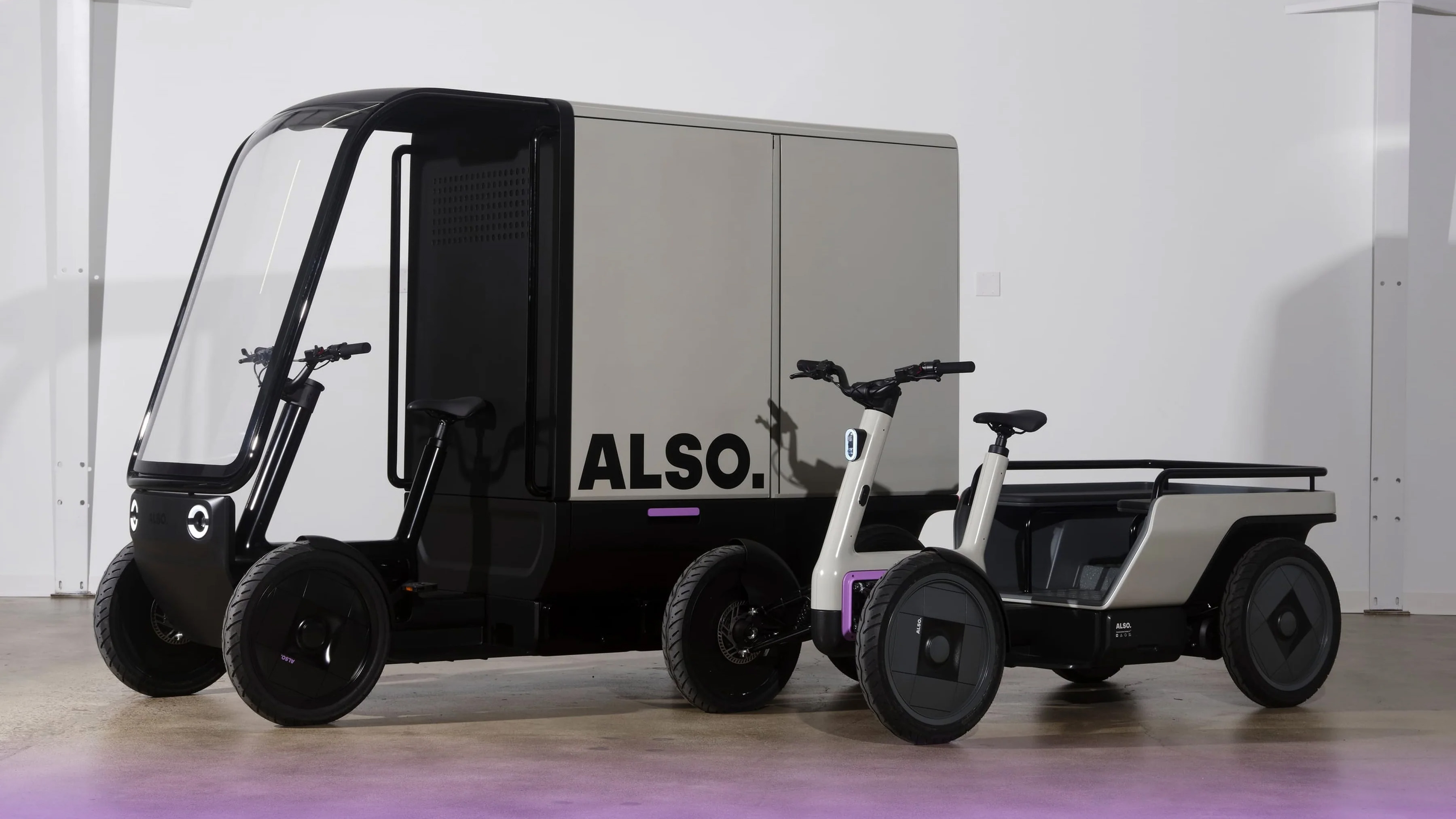 Two Also TM-Q EVs. One is fitted with a large enclosed storage cabin. The other shows the narrow device without any attachments.