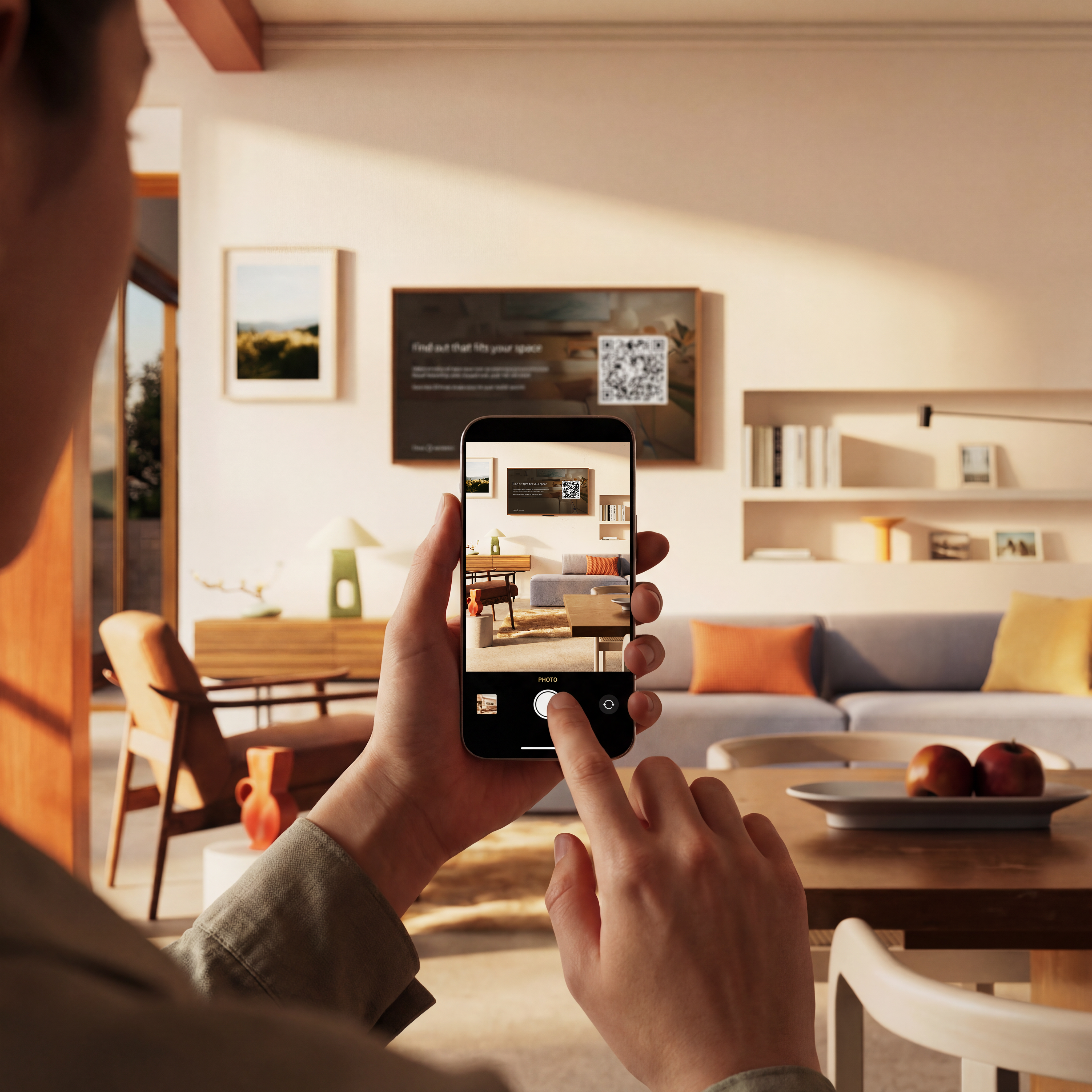 A person holding up a phone taking photos of a room with an Ember Artline TV on the wall.