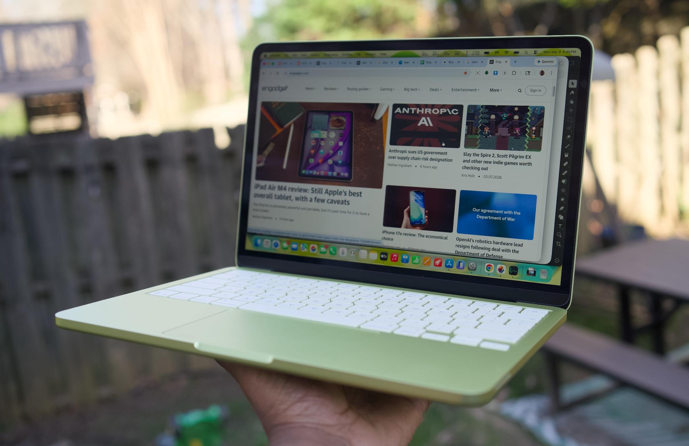 A person's hand holding the MacBook Neo