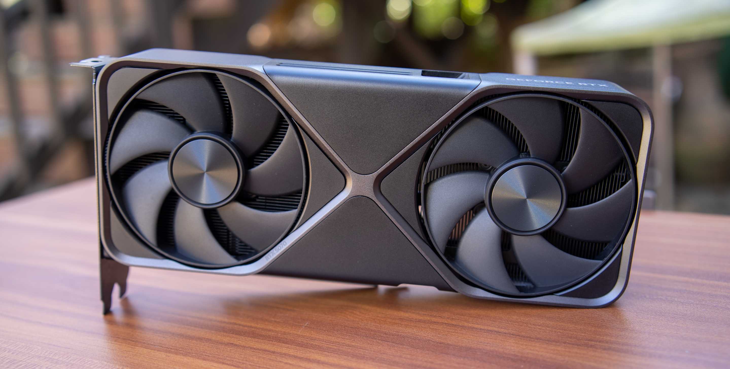A Founders Edition NVIDIA RTX 5080 sits on a wood desk.