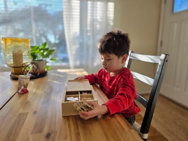 Child sitting at a table playing with a puzzle.