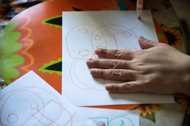 A photo of a hand on top of a white piece of paper with orange circles drawn on it.