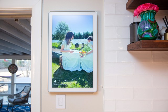 A digital photo frame wall mounted on a white wall.