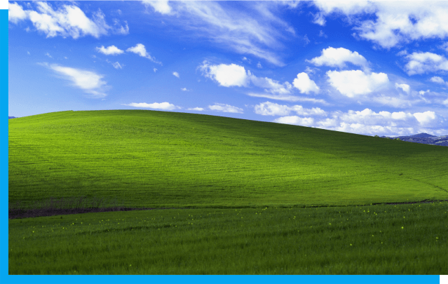 Photo of a green rolling hill with a bright blue sky.