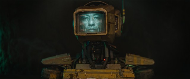A humanoid robot with a monitor for a head displaying an actual human face.