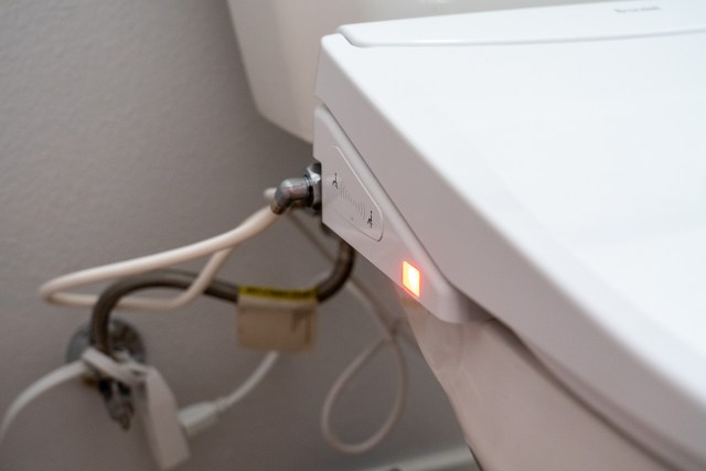 Close up of the side panel and water hookups of a bidet toilet seat