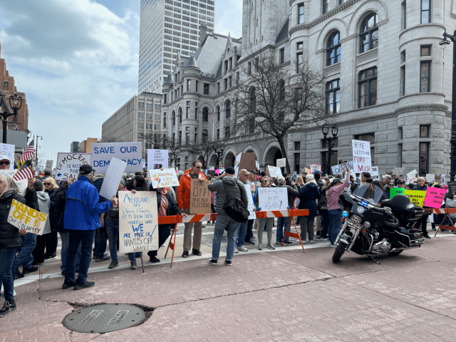 People holding protest signs while standing behind a barricade.