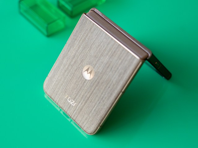 Motorola Razr with wood back panel partially unfolded on a green background