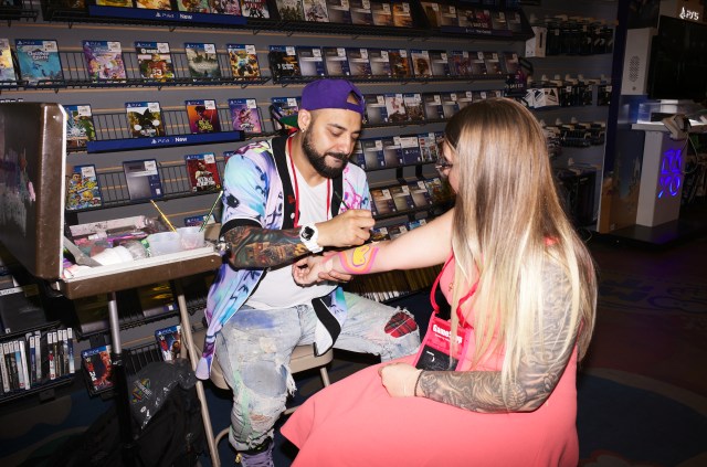 A body painter (left) paints a customer’s arm (right).