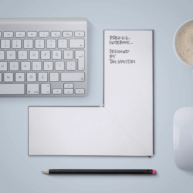 Keyboard with L-shaped notebook next to di and a pen below.
