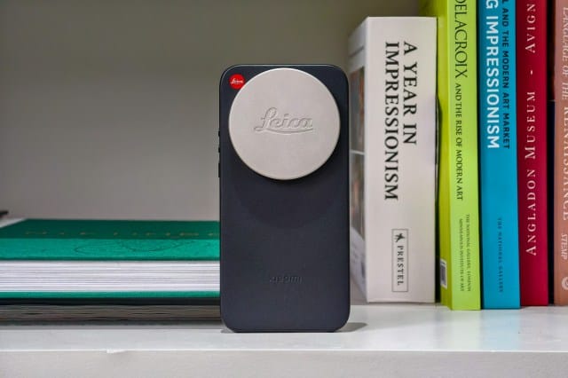 Photo of the Xiaomi Leica Leitzphone on a bookshelf, in a case with a Leica lens cap