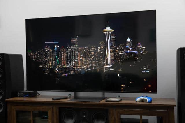 The Sony Bravia 7 II RGB LED TV on a dark wooden credenza displaying a city nighttime scene.