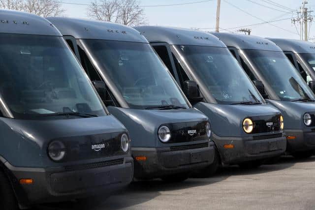 A line of parked dark blue Rivian Amazon branded delivery vans.
