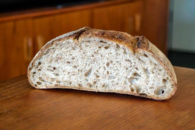 Photo of a loaf of sourdough bread cut in half on a wooden table