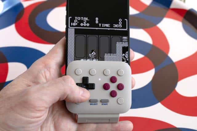 A person playing a Game Boy game with the 8BitDo FlipPad attached to an iPhone.