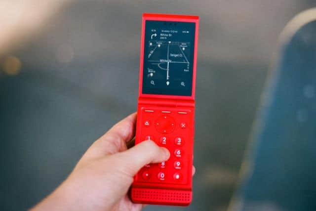A red flip phone, open, showing directions.
