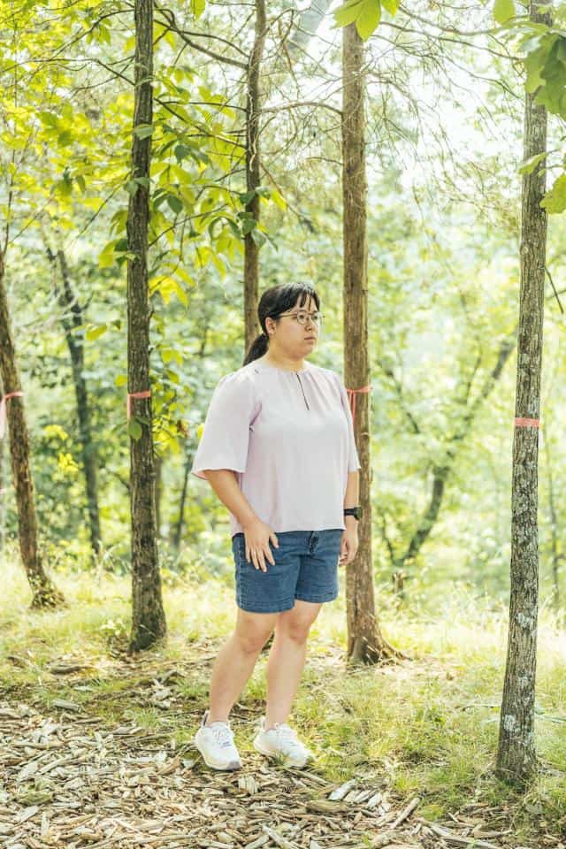 Madison Taggart stands in her backyard among trees marked by pink ribbons to show where a proposed transmission tower would go.