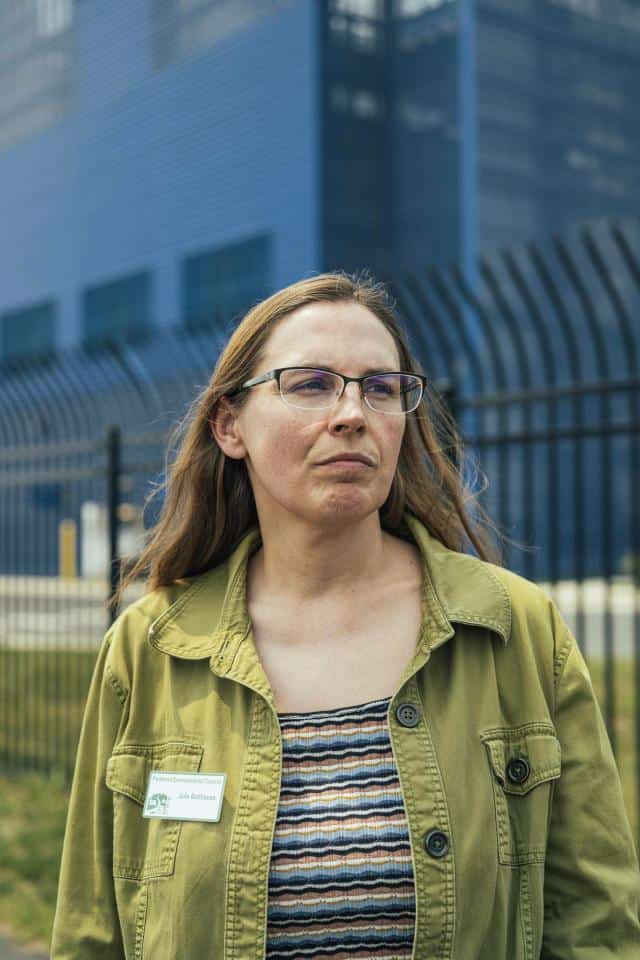 Piedmont Environmental Council land use director Julie Bolthouse stands in front of the blue Vantage VA2 data center in Ashburn, Virginia.